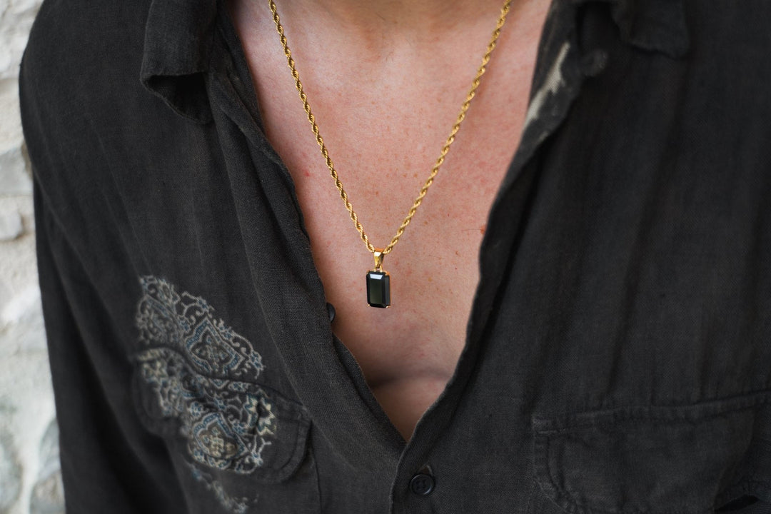 Man in a dark linen shirt wearing the Void Onyx pendant on a gold rope chain